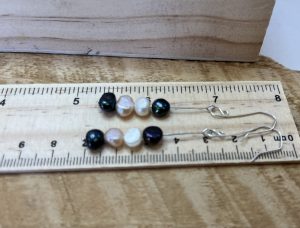 2 dangly earings with 4 spheres on each being measured on a ruler
