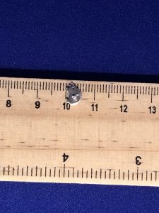 A sterling silver hedgehog stud being measured on a ruler